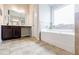 Spacious bathroom featuring a large tub, vanity and neutral tile flooring at 8045 Hillside Climb Way, Snellville, GA 30039