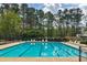 Community pool with lane markers, surrounded by lounge chairs, mature trees, and privacy fencing at 8045 Hillside Climb Way, Snellville, GA 30039