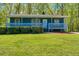 Charming blue house featuring a cozy front porch, complemented by a well-maintained, lush green lawn and mature trees at 166 Rustin Dr, Dallas, GA 30157