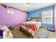 Colorful bedroom with purple and blue walls, a plush bed and unique decorations at 3889 Elm Trace Dr, Loganville, GA 30052