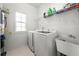 Bright laundry room with modern appliances, shelving, and a utility sink at 3889 Elm Trace Dr, Loganville, GA 30052