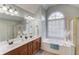 Bright bathroom featuring a dual sink vanity, a tub under arched window and a glass shower stall at 4766 Cedar Wood Sw Dr, Lilburn, GA 30047