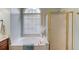 Corner bathtub sits below a window with blinds and is next to a shower with gold trim at 4766 Cedar Wood Sw Dr, Lilburn, GA 30047