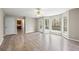 Living room with wood floors, ceiling fan, backyard view through bay window, and access to kitchen at 300 Radner Run, Lawrenceville, GA 30043