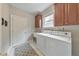 Bright laundry room featuring white front-loading machines, overhead cabinets and a utility sink at 3311 Keenland Rd, Marietta, GA 30062