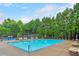 Outdoor community pool surrounded by lounge chairs, mature trees, and a fenced-in tennis court at 3311 Keenland Rd, Marietta, GA 30062
