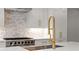 Close-up of kitchen featuring a gold faucet, stainless steel appliances and designer backsplash at 3932 Boston Common St, Suwanee, GA 30024