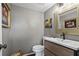 Chic powder room with gray walls, modern vanity, and decorative gold framed mirror and floral painting at 1 James River Ne Pl, Atlanta, GA 30342
