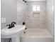 Bright bathroom featuring a sleek vanity and a modern shower-tub combo with stylish marble-like tiling and a small window at 2077 Perkerson Rd, Atlanta, GA 30310
