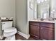 View of the half bathroom with dark brown cabinets, wooden floors, and decorative art on the walls at 815 Commerce Trl, Canton, GA 30114