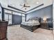 View of a primary bedroom featuring a trey ceiling, a ceiling fan, large windows, and an ornate king bed at 815 Commerce Trl, Canton, GA 30114