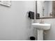 Modern half-bathroom featuring a pedestal sink with a silver faucet, mirror, and gray walls at 1427 Lanier Vista Dr, Sugar Hill, GA 30518