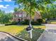Attractive two-story brick home with a manicured front lawn, mature trees, and a long driveway leading to a two-car garage at 602 Davenport Pl, Canton, GA 30115