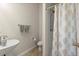 Well-lit half bathroom featuring pedestal sink, toilet, and tiled shower with curtain at 404 Prague Way, Hampton, GA 30228