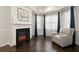 Cozy sitting room features electric fireplace, hardwood floors, and comfortable armchair at 404 Prague Way, Hampton, GA 30228