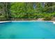 Inviting in-ground pool surrounded by a concrete deck and mature trees at 3127 Hidden Forest Dr, Snellville, GA 30078