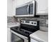 A close up of the stove and microwave featuring sleek stainless steel appliances and tiled backsplash at 6703 Gallant Se Ct, Mableton, GA 30126