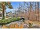 Scenic backyard with tranquil pond, small waterfall, lush landscaping, and mature trees at 725 Links View Dr, Sugar Hill, GA 30518