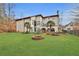 Estate backyard with view of stucco home and mature trees with lush landscaped yard and fire pit at 725 Links View Dr, Sugar Hill, GA 30518