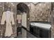 Dark marble bathroom with modern tub, shower, and fixtures. Robe hanging on wall at 725 Links View Dr, Sugar Hill, GA 30518
