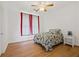 Well-lit bedroom with a single bed, a bedside table, wood floors, and red and white curtains at 725 Links View Dr, Sugar Hill, GA 30518