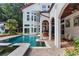 Back of home showcases in-ground pool, spa and outdoor covered porch with brick patio and architectural features at 725 Links View Dr, Sugar Hill, GA 30518