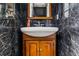 Classic powder room exhibits dark marble walls, wood vanity with sink, and a wood-framed mirror at 725 Links View Dr, Sugar Hill, GA 30518