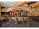 Spacious home wet bar with unique thatched roof over dark countertop bar with seating and black marble floors at 725 Links View Dr, Sugar Hill, GA 30518
