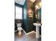 Stylish powder room with dark green walls, pedestal sink, round mirror, and ample natural light at 1840 Wellston Dr, Lawrenceville, GA 30043