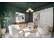 Cozy sitting room showcases modern decor, with white chairs, olive walls, a designer light fixture, and an open staircase at 1840 Wellston Dr, Lawrenceville, GA 30043