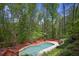 Backyard with a large swimming pool, deck, and a backdrop of mature trees and greenery at 2000 Old Dominion Rd, Atlanta, GA 30350