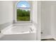 Bright bathroom features a soaking tub under a large window and a separate shower at 7240 Raintree Loop, Jonesboro, GA 30236