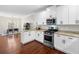 Open kitchen with white cabinetry, granite counters, stainless steel appliances, and hardwood floors at 1902 Glen Ivy, Marietta, GA 30062