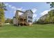 Back exterior view showcases a multi-story home with a wooden deck overlooking a sprawling green lawn at 553 Somersby Dr, Dallas, GA 30157