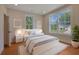 Bright bedroom featuring a comfortable bed, white nightstands, and two large windows overlooking the lawn at 553 Somersby Dr, Dallas, GA 30157