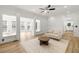 Bright living room featuring ceiling fan, modern furniture, light wood floors, and views into sunroom and kitchen at 1420 Midland Way, Lawrenceville, GA 30043