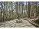 Outdoor fire pit area with stone pavers and surrounding woods, perfect for entertaining at 4284 Windy Gap Nw Ct, Kennesaw, GA 30144