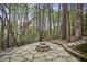 Stone patio with a cozy fire pit area nestled among mature trees and landscaping at 4284 Windy Gap Nw Ct, Kennesaw, GA 30144