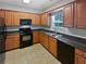 Kitchen featuring black appliances, wood cabinets, neutral countertops, and a window above the sink at 5763 Mitchell Chase Trl, Mableton, GA 30126