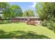 View of the backyard with a wooden deck, flat yard, brick house, and tall, mature trees at 120 Westwood Nw Dr, Marietta, GA 30064