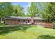 The backyard offers a flat grassy area, brick home, wooden deck, and mature trees at 120 Westwood Nw Dr, Marietta, GA 30064