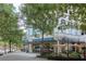 Street-level view of a building with outdoor dining and ample shade trees at 860 Peachtree Ne St # 1010, Atlanta, GA 30308