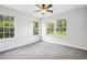 Bright bedroom featuring three large windows, plush carpet, and a modern ceiling fan at 961 Old Conyers Rd, Stockbridge, GA 30281