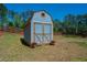 Blue shed with double doors sits in the backyard, accented with flower pots and surrounded by trees at 5138 Price Dr, Suwanee, GA 30024