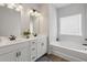Bright bathroom features double sinks, white cabinets, and a tub with a shower, complemented by warm lighting at 375 Crider Ct, Woodstock, GA 30188