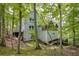 Exterior view of a gray home surrounded by a wooded landscape, with a glimpse of the backyard and stairs at 7470 Princeton Trce, Sandy Springs, GA 30328