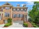 Beautiful brick townhome featuring a two-car garage and charming architectural details with stairs leading up to the front door at 1561 Mosaic Way, Smyrna, GA 30080