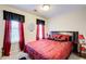 A bedroom with red silk bedding, black accents, and natural light from window at 2121 Silva Ct, Conley, GA 30288