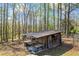 Exterior view of a small, run-down shed, set in a densely wooded area at 700 Stewart Rd, Covington, GA 30016