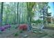 Beautiful backyard featuring a playground, mature trees, and colorful azalea bushes, as viewed from inside the home at 1039 Smyrna Rd Sw, Conyers, GA 30094
